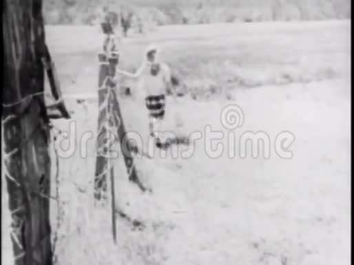 年轻女子走在篱笆穿过田野的后景视频的预览图