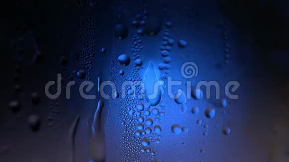一滴水在一个玻璃特写宏观与闪闪发光的波克在蓝色模糊的背景抽象滴水雨滴视频的预览图