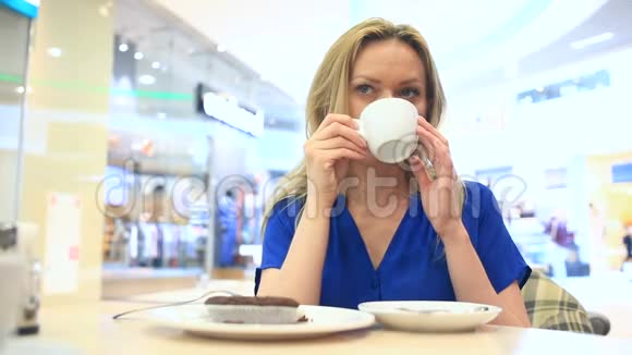 在咖啡馆里喝着咖啡和巧克力蛋糕的女人视频的预览图