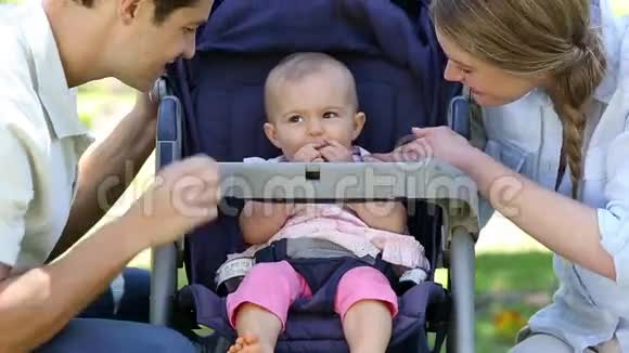 快乐的父母在公园的婴儿车里照顾女婴视频的预览图