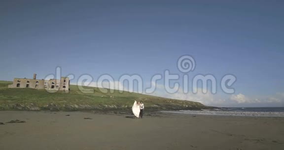 微笑着新婚夫妇跑到海滩上的镜头前视频的预览图
