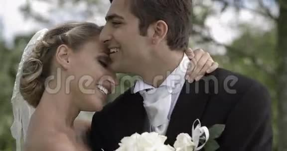 新郎在公园里亲吻他漂亮的新妻子视频的预览图