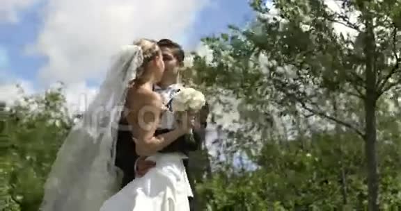 新郎在外面亲吻他漂亮的新妻子视频的预览图