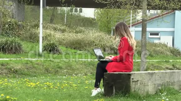 穿红裙子的女孩拿着笔记本电脑在街上工作视频的预览图