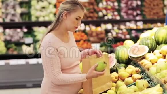 带包的孕妇在杂货店买梨视频的预览图
