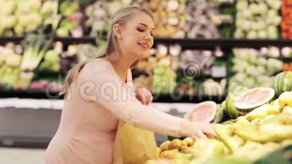 带包的孕妇在杂货店买梨视频的预览图