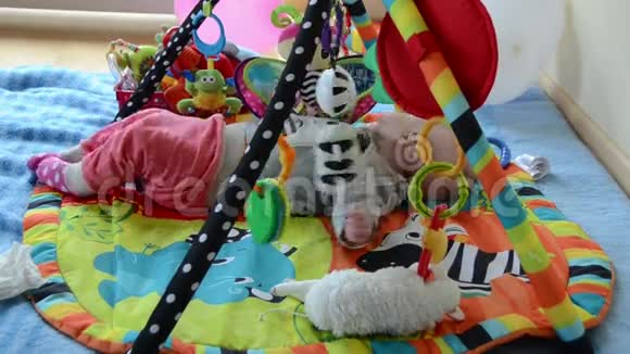 新生儿可爱的宝宝在五颜六色的发育垫上玩玩具视频的预览图