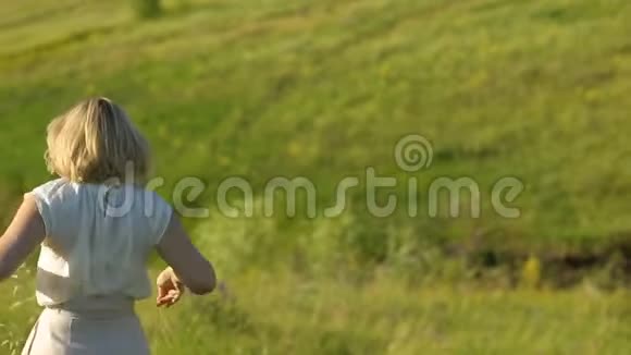 肖像快乐的年轻女子在一个夏天散步在田野近距离年轻漂亮的女人在夏天的田野里散步微笑视频的预览图