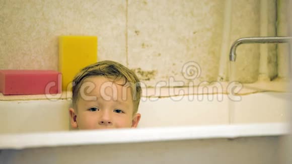 微笑的小男孩坐在浴室里视频的预览图