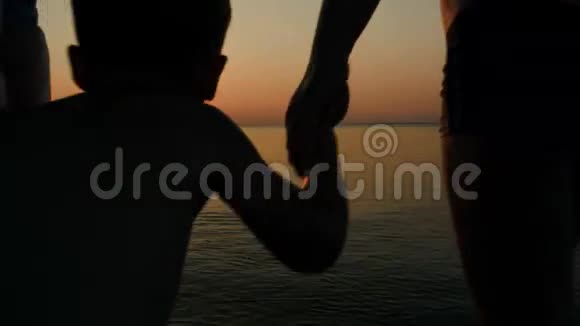 日落时分父母和儿子在海上玩球视频的预览图