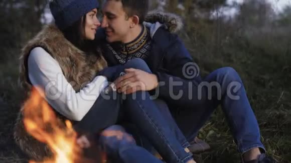 浪漫的情侣在篝火旁休息微笑亲吻和爱抚视频的预览图