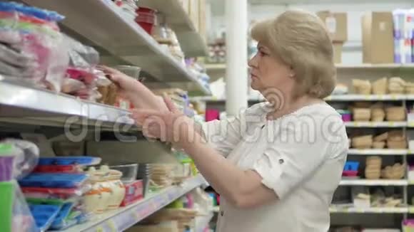 老妇人在超市里选择厨房配件在商店里购物高级女性仔细分析视频的预览图