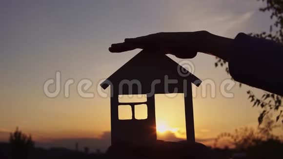 太阳落山时特写双手握住房子视频的预览图