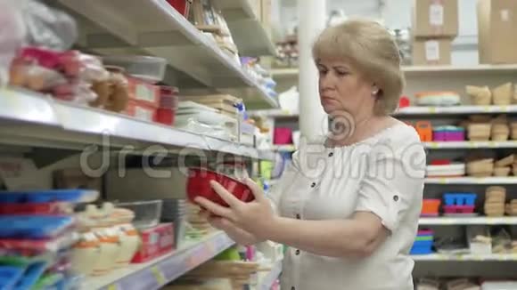 老妇人在超市里选择厨房配件在商店里购物高级女性仔细分析视频的预览图