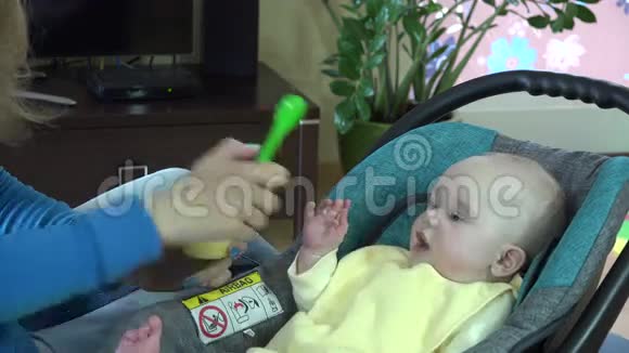 妈妈在汽车座位上喂女婴蔬菜粥视频的预览图