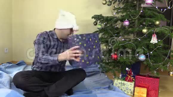 幸福的丈夫抓住礼物盒放在圣诞树下视频的预览图
