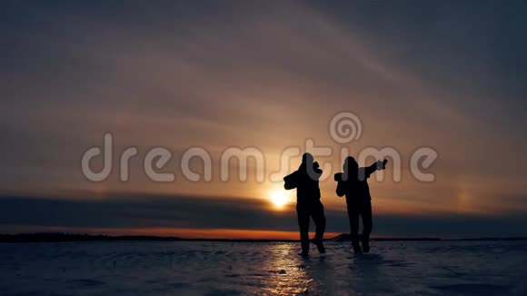 两名游客剪影男子去日落旅行者旅游概念二人摄影师走过雪地视频的预览图
