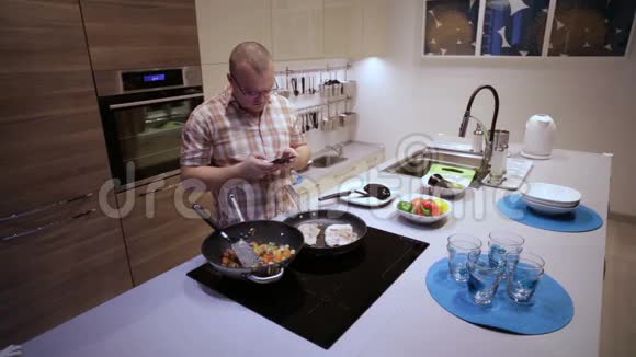 男人做饭看着电话视频的预览图