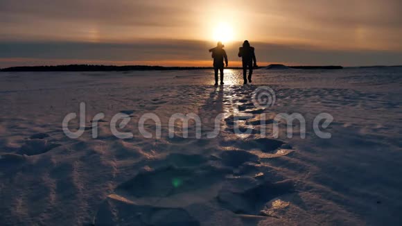 两名游客剪影男子去日落旅行者旅游概念二人摄影师走过雪地视频的预览图