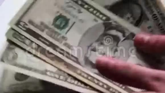 女人数着桌上的一小块美元钞票白色背景的宏观特写视频的预览图