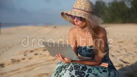 年轻女子在沙滩上用电脑聊天视频的预览图