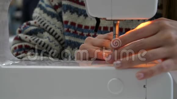 女孩把一个图案钉在布料上女人的手缝在缝纫机上视频的预览图