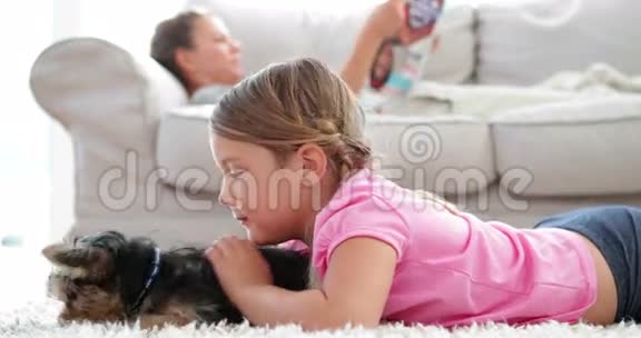 小女孩和小狗玩耍妈妈在沙发上看书视频的预览图