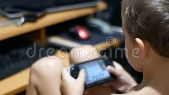 小孩坐在家里的椅子上玩手提游戏机视频的预览图