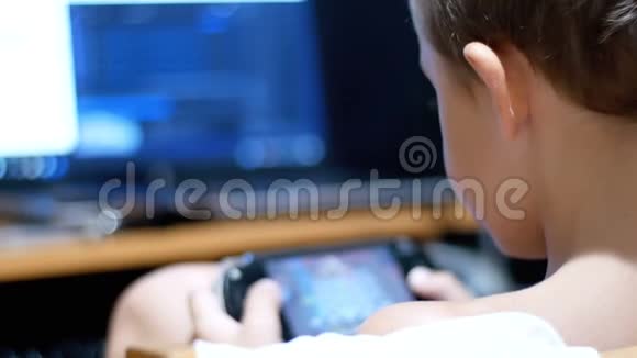 小孩坐在家里的椅子上玩手提游戏机视频的预览图