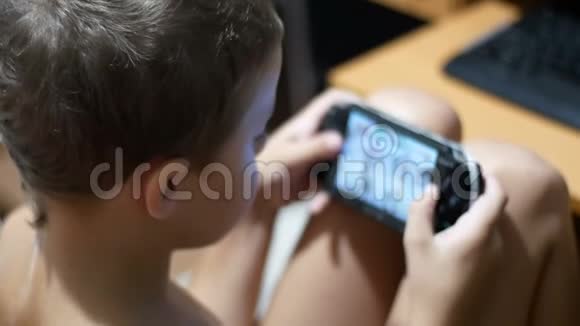 儿童正在玩便携式游戏控制台坐在家里的椅子上视频的预览图