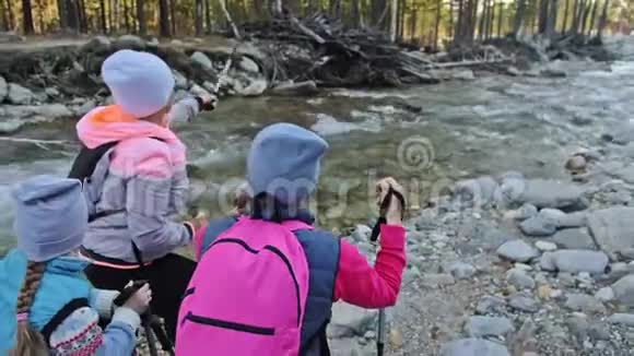 女人在大自然中行走靠近山河女孩和孩子使用跋涉棒和北欧杆视频的预览图