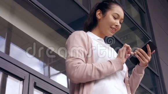 亚洲女商人在外面用手机视频的预览图