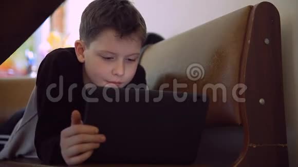有平板电脑的少年躺在沙发上浏览互联网生活方式视频的预览图