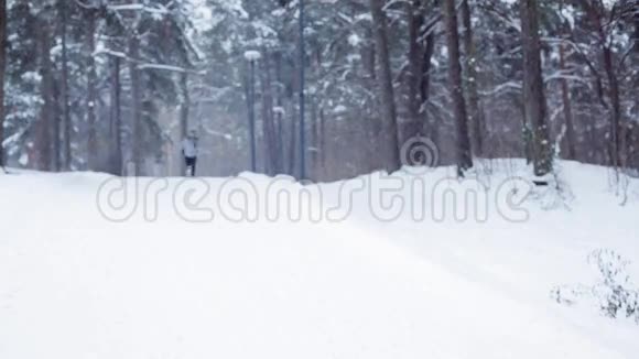 在白雪覆盖的冬天森林道路上奔跑的人视频的预览图