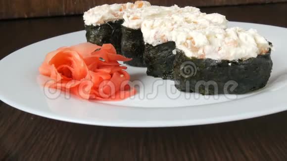 一个白色的大盘子上面放着四个巨大的寿司黑吉里旁边是粉红色的生姜和绿色的芥末视频的预览图