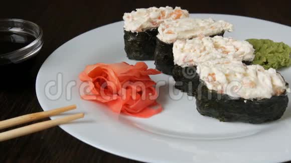 一个白色的大盘子上面放着四个巨大的寿司黑吉里旁边是粉红色的生姜和绿色的芥末视频的预览图