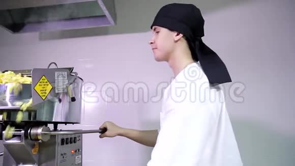 年轻迷人的白种人穿着黑色头巾的男厨房工人用爆米花自动机加工玉米视频的预览图
