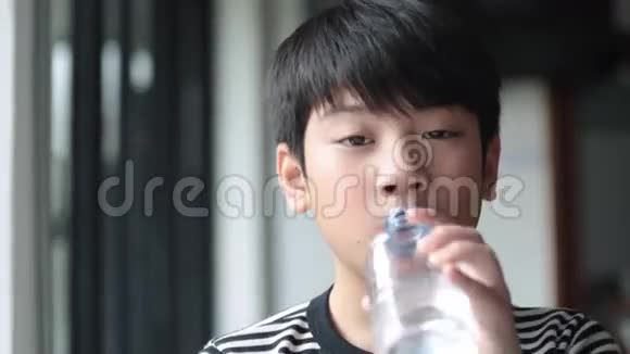快乐的亚洲可爱男孩从瓶子里喝水视频的预览图