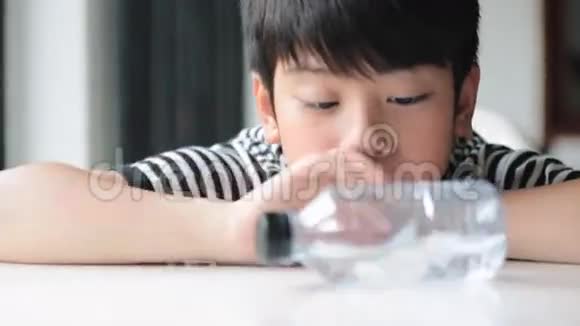快乐的亚洲可爱男孩从瓶子里喝水视频的预览图
