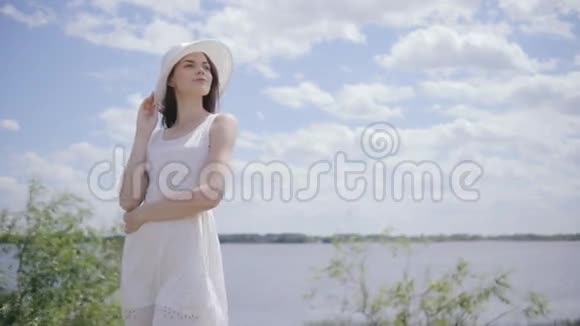 一个年轻漂亮的女人在水边天空满是云视频的预览图
