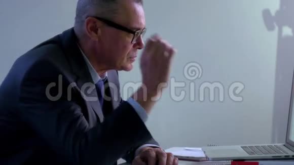 在办公室用电脑工作的老商人4他摘下眼镜对着屏幕看视频的预览图
