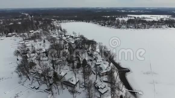 在冰雪覆盖的房屋上飞翔在冰冻的湖滨视频的预览图