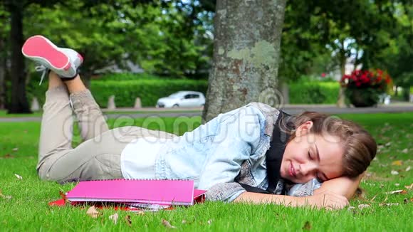快乐的学生躺在草地上接她的电话视频的预览图