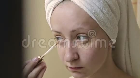 年轻漂亮的女人在浴室里用遮瑕膏视频的预览图