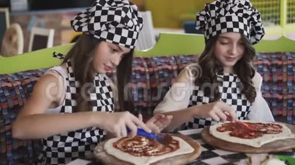 两个穿制服的快乐女孩在4K咖啡馆的大师班做披萨视频的预览图