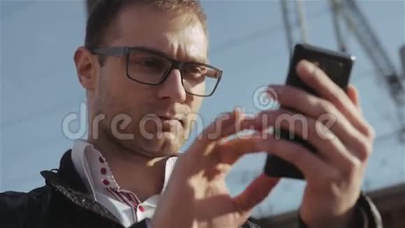 英俊的年轻人站在外面发短信的肖像视频的预览图