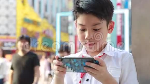 在日本东京步行街附近使用智能手机的快乐亚洲男孩视频的预览图