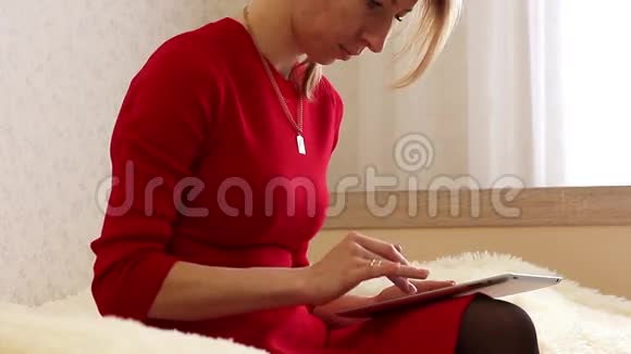 时尚女孩用平板智能手机和信用卡在线购买坐在家里的床上视频的预览图