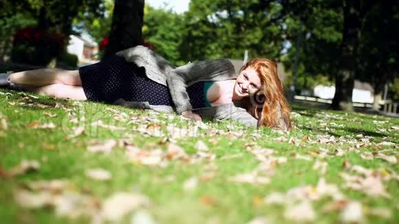 快乐的红发人躺在绿色的草坪上放松视频的预览图