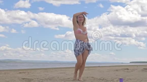 快乐的年轻女子在蓝色的海水中在热带海滩跳舞视频的预览图